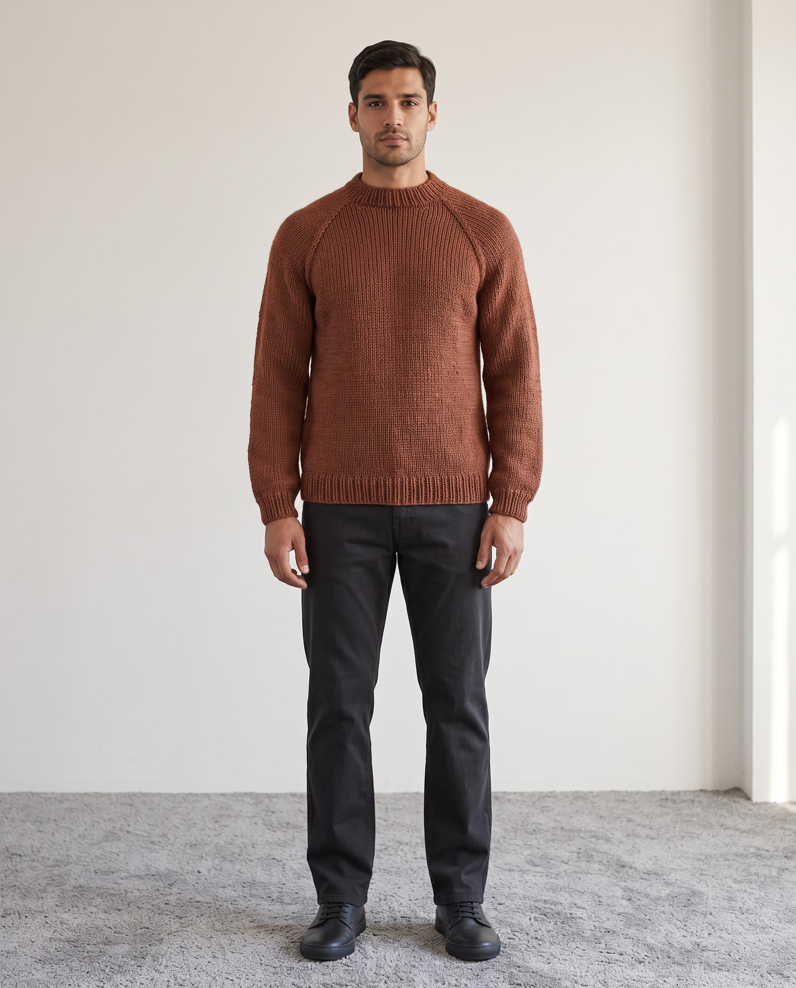 Model wearing the rust hand-knit sweater in a bright room with grey carpet