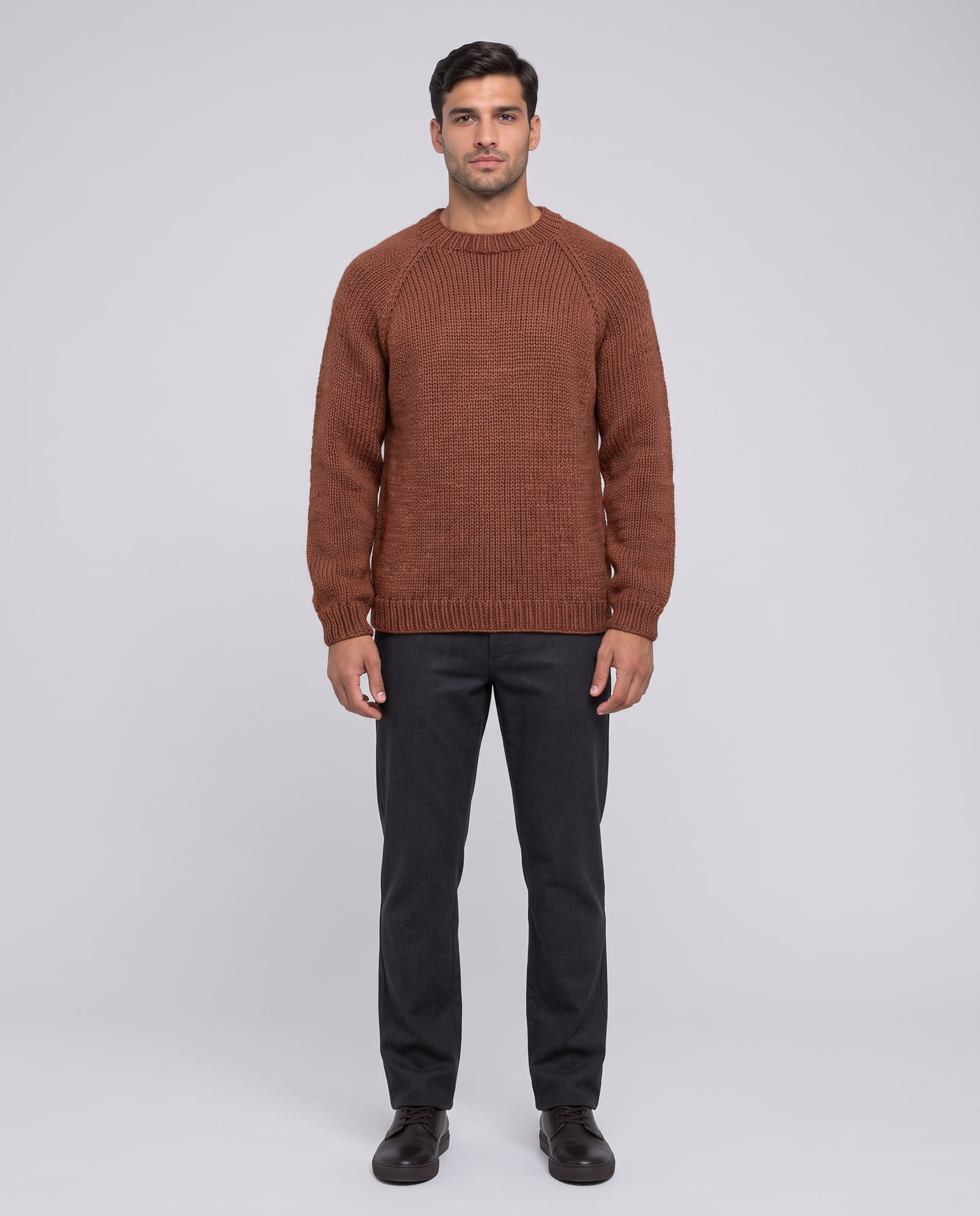 Model wearing the rust hand-knit sweater in a light-grey studio