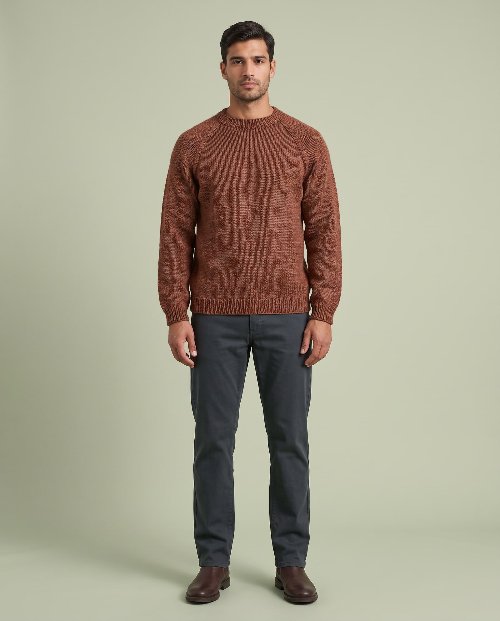Model wearing the rust hand-knit sweater in a pale sage studio