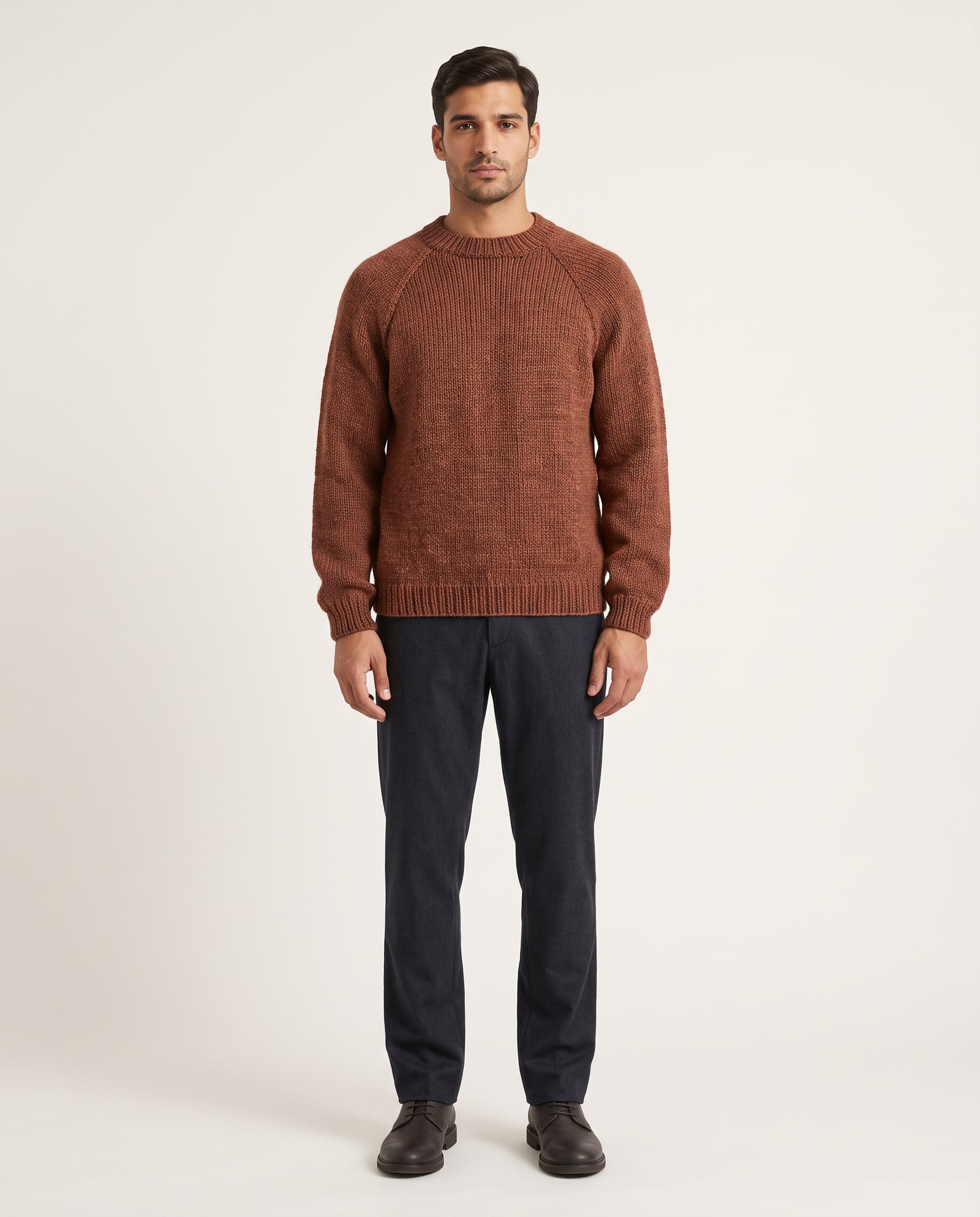 Model wearing the rust hand-knit sweater in a soft white studio