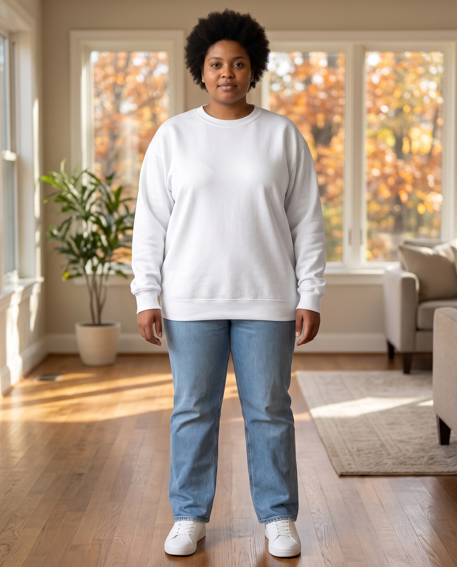 Model wearing the white crewneck sweatshirt in a sunlit room with autumn trees outside