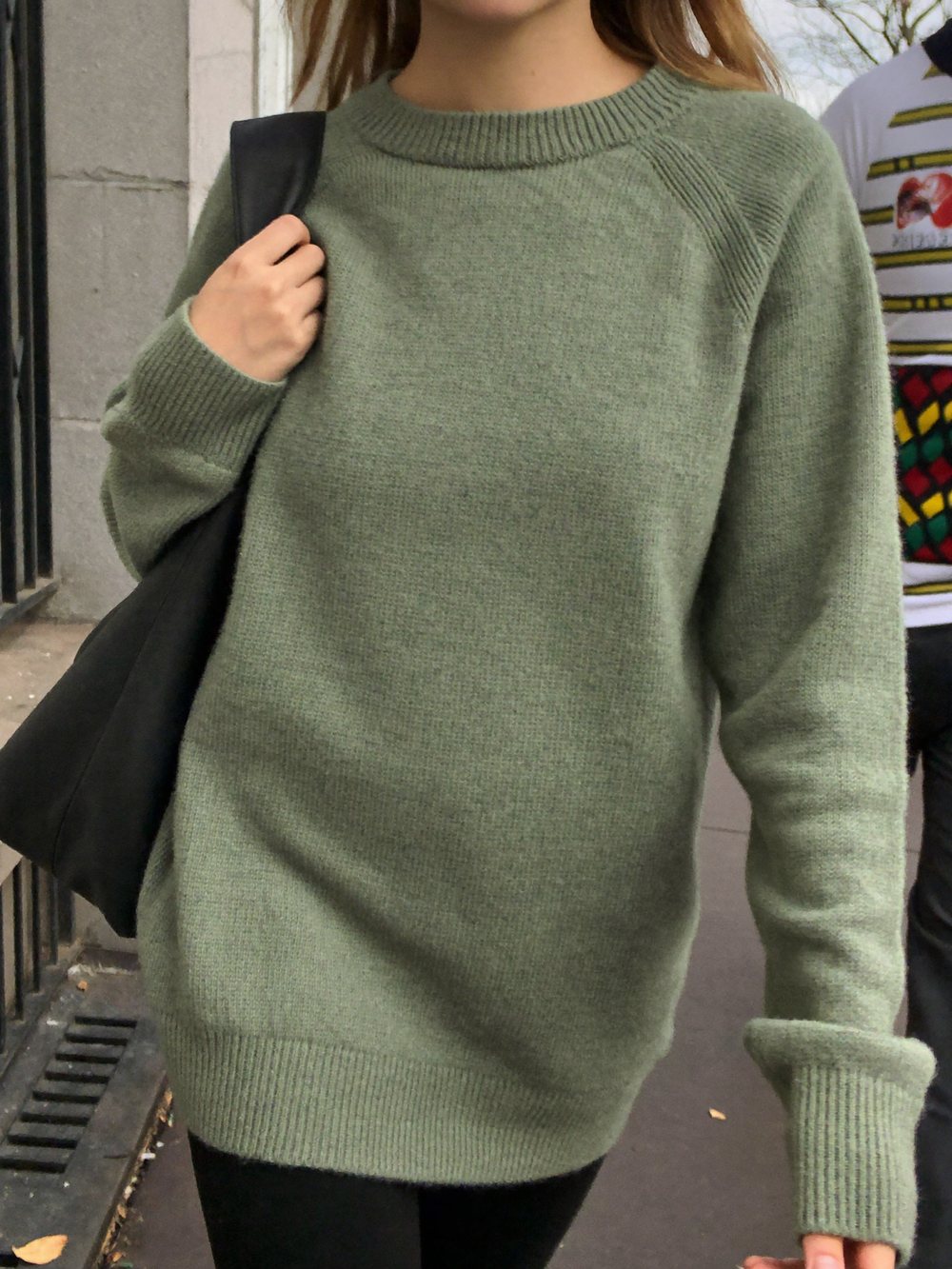Candid street photograph of the sage ribbed crewneck worn with a shoulder bag