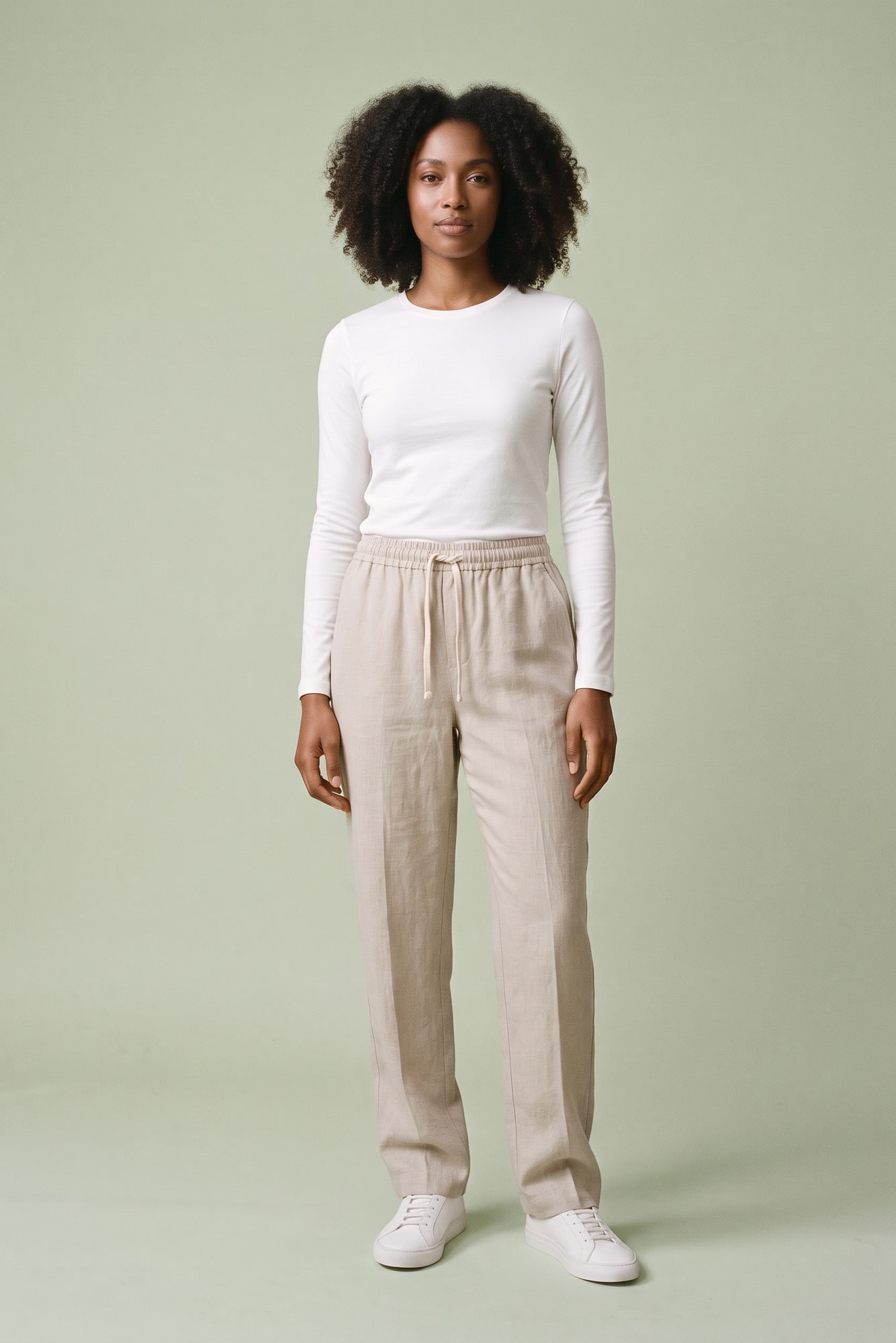 Model on a pale sage backdrop in stone drawstring trousers