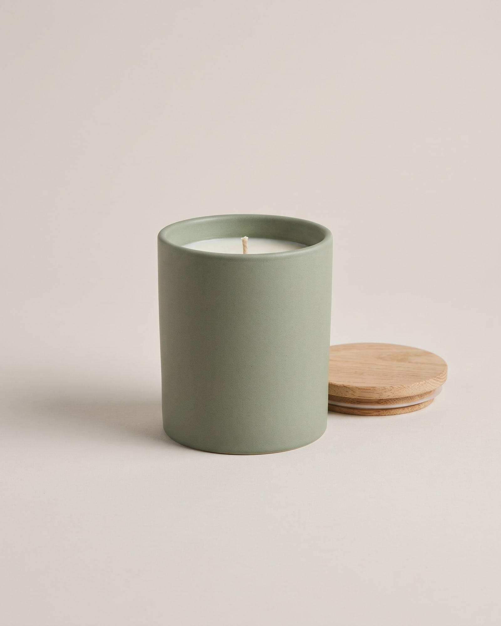Sage ceramic candle with an oak lid on light grey