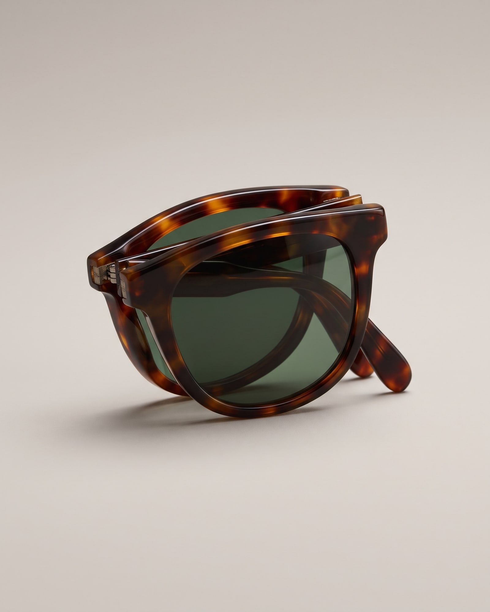 Tortoiseshell sunglasses with green lenses on light grey