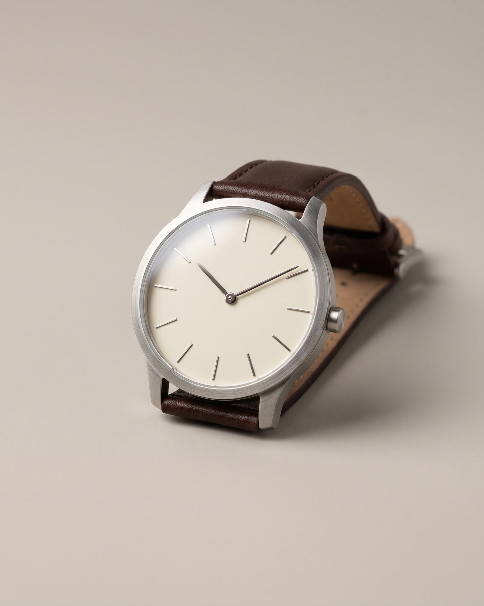 Steel watch with an ivory dial and brown leather strap on light grey