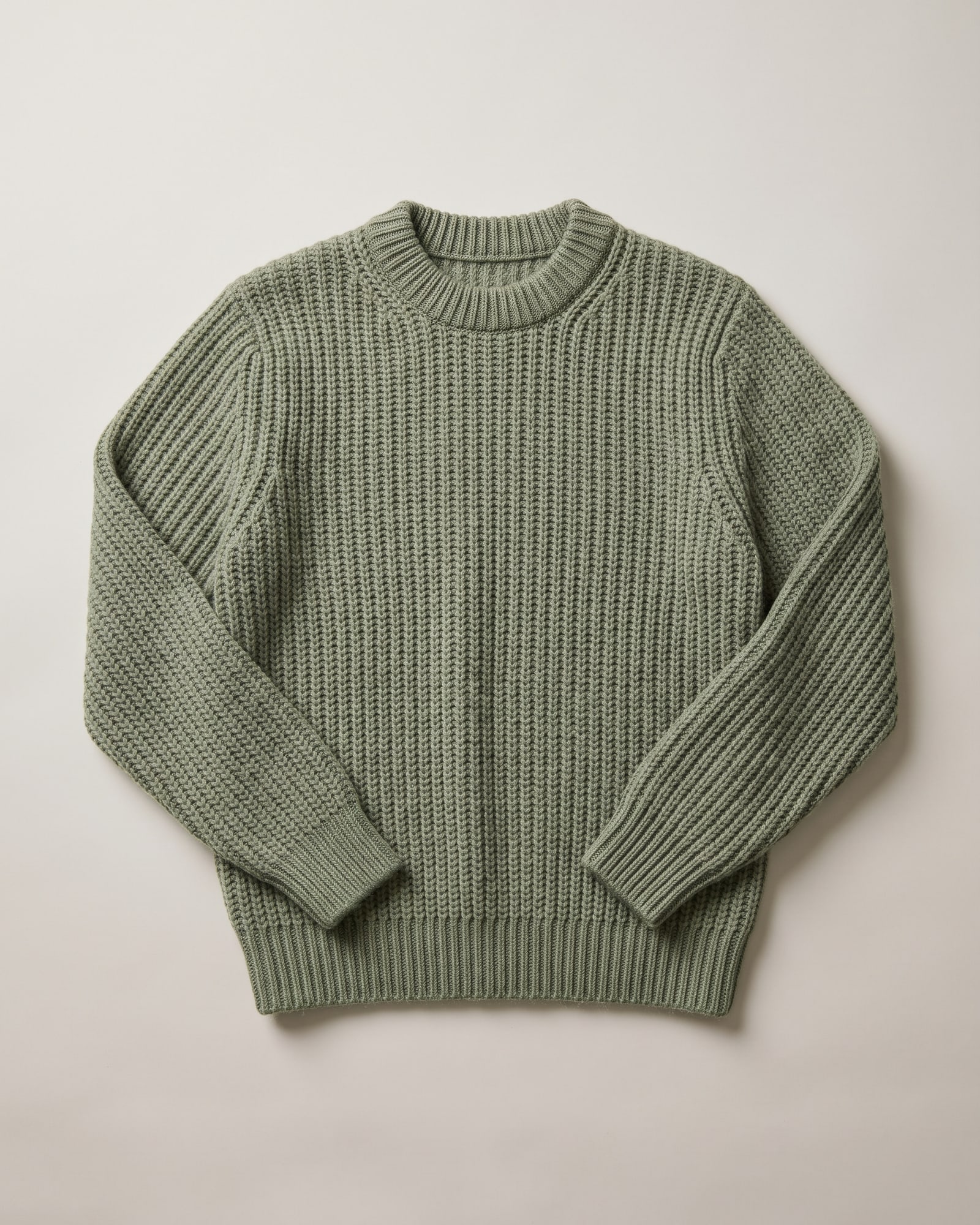 Flat-lay of a sage ribbed crewneck sweater on light grey